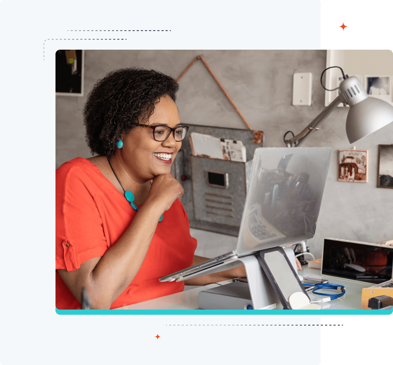 Imagen de una mujer sonriente mirando su computadora portátil que está sobre un soporte elevado.