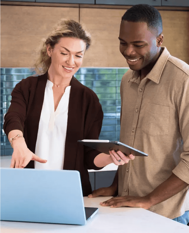 Hombre y mujer sonriendo mientras miran una computadora portátil.